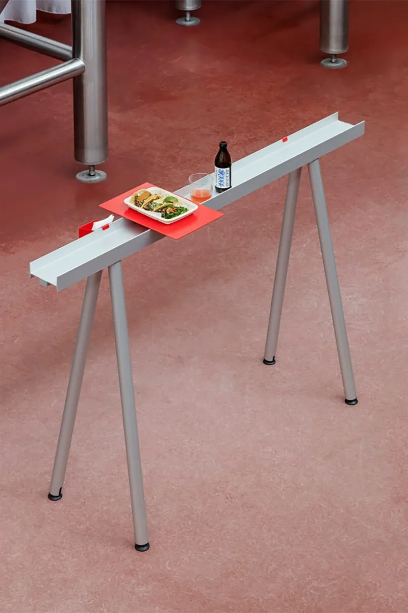 Table design moderne avec plat, boisson sur fond de sol rouge.