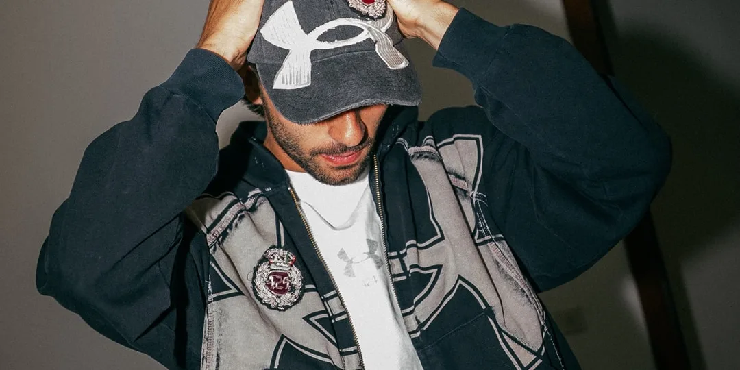 Homme portant une casquette et un sweat à capuche, regard vers le bas.