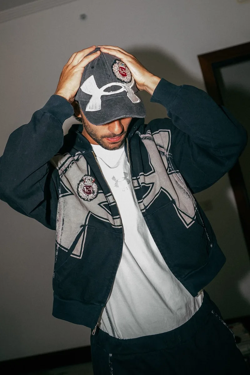 Homme portant une casquette et un sweat à capuche avec logo en noir et blanc.