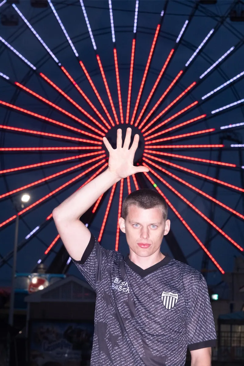 Homme levant la main devant une grande roue illuminée
