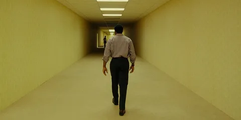 Homme marchant dans un long couloir jaune.