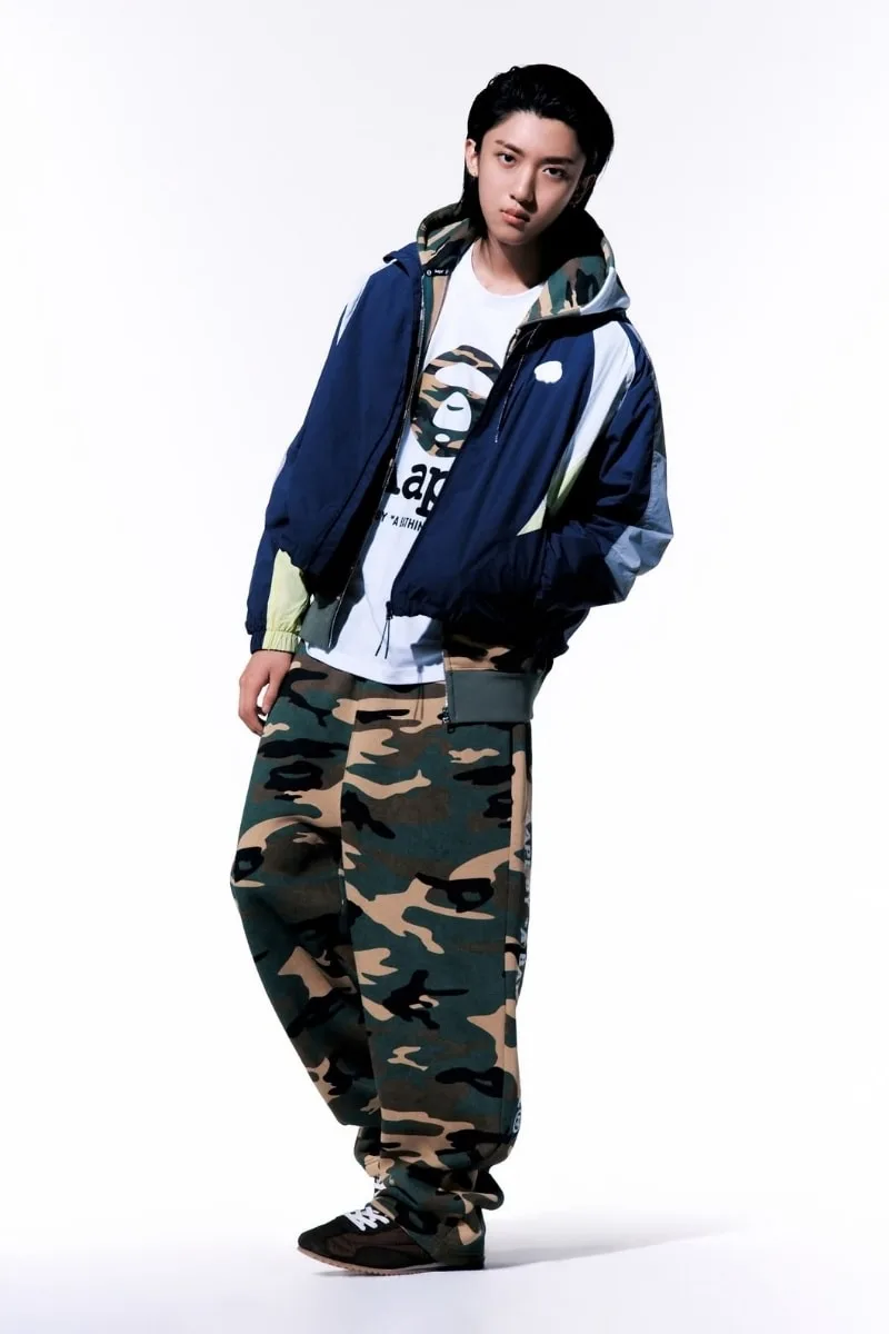 Personne en tenue décontractée avec pantalon camouflage et veste bleue.