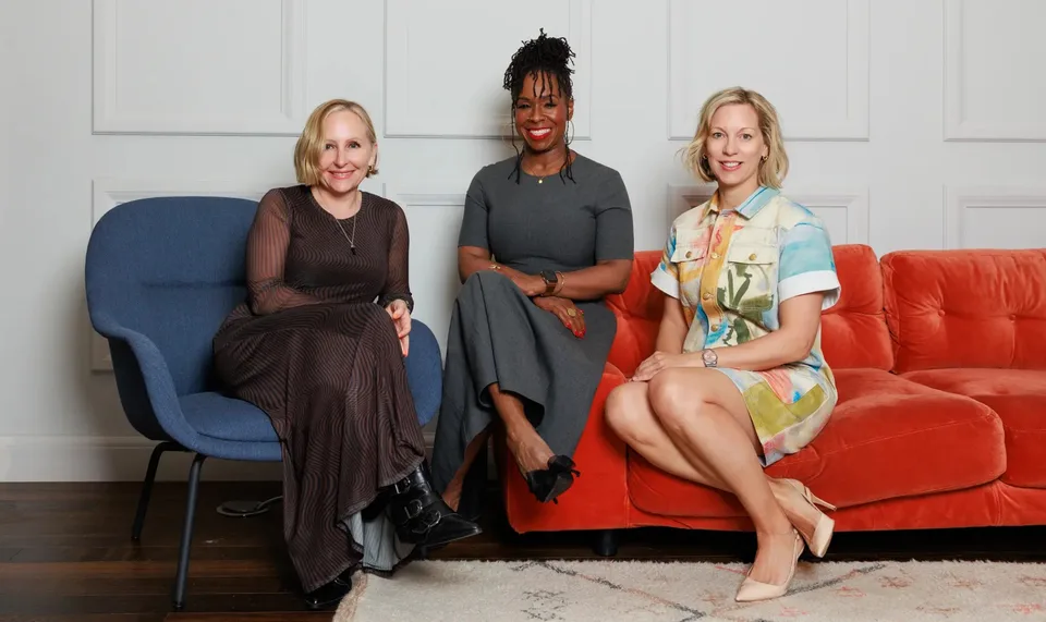 Trois femmes assises sur des fauteuils et un canapé coloré.
