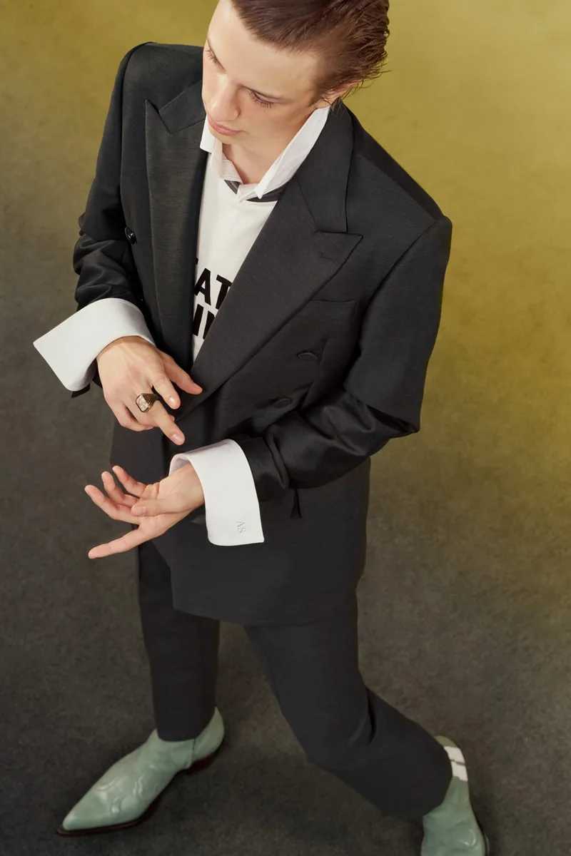 Homme en costume sombre avec chemise blanche et bottes vertes