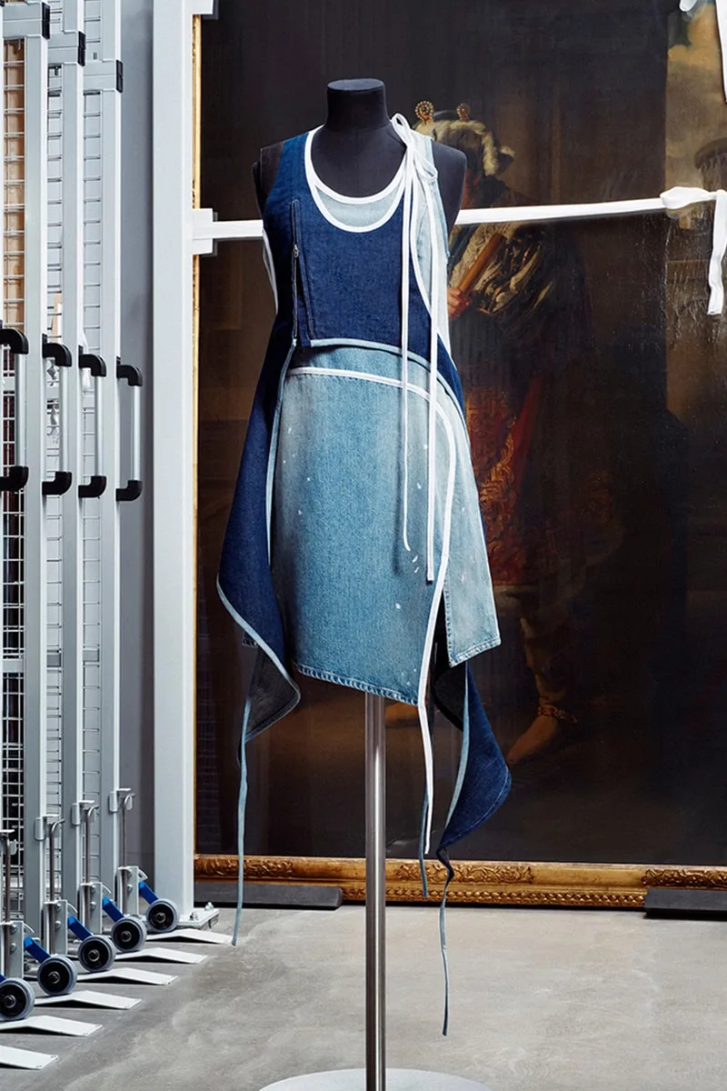 Mannequin avec robe en jean superposée, fond de tableau.