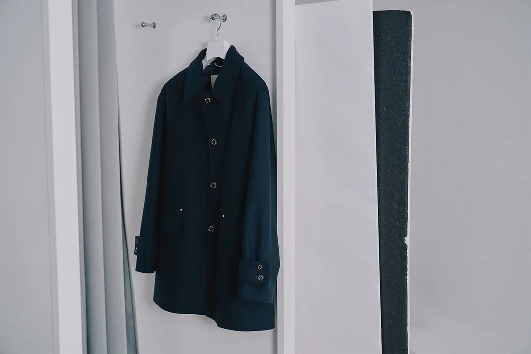 Manteau noir suspendu sur un cintre dans un placard blanc.