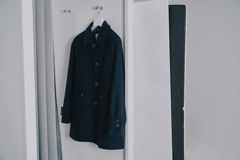 Manteau noir suspendu sur un cintre dans un placard blanc.