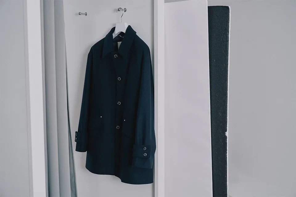 Manteau noir suspendu sur un cintre dans un placard blanc.