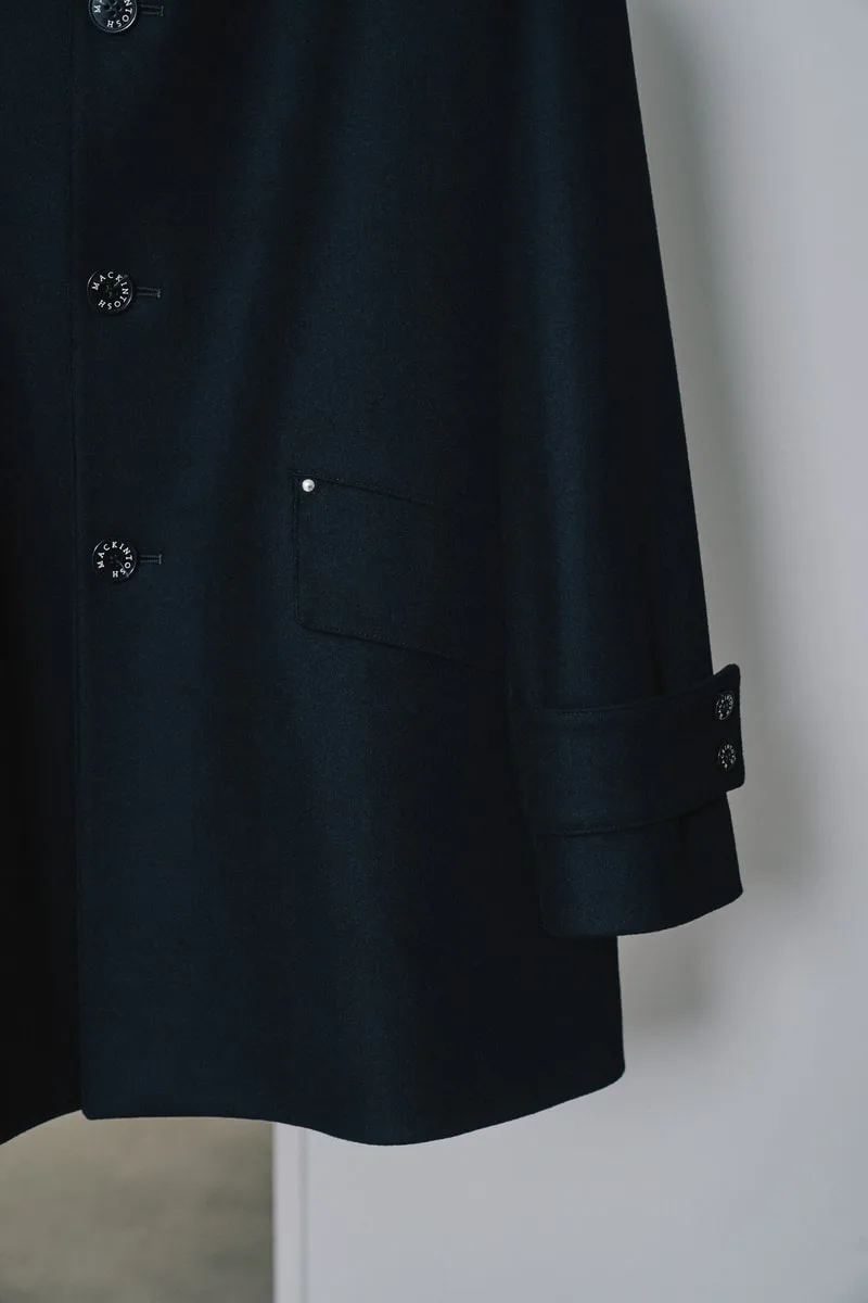 Partie d'un manteau bleu foncé avec boutons et poche.