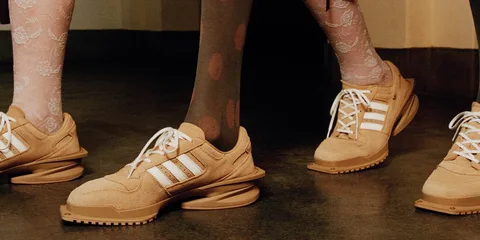 Des chaussures beiges avec des bandes blanches, portées avec des collants à motifs.