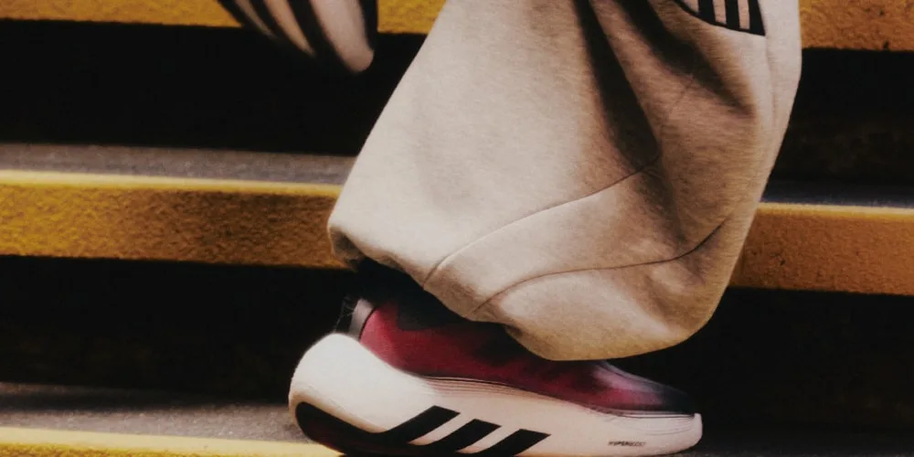 Personne portant des baskets Adidas sur des marches jaunes.