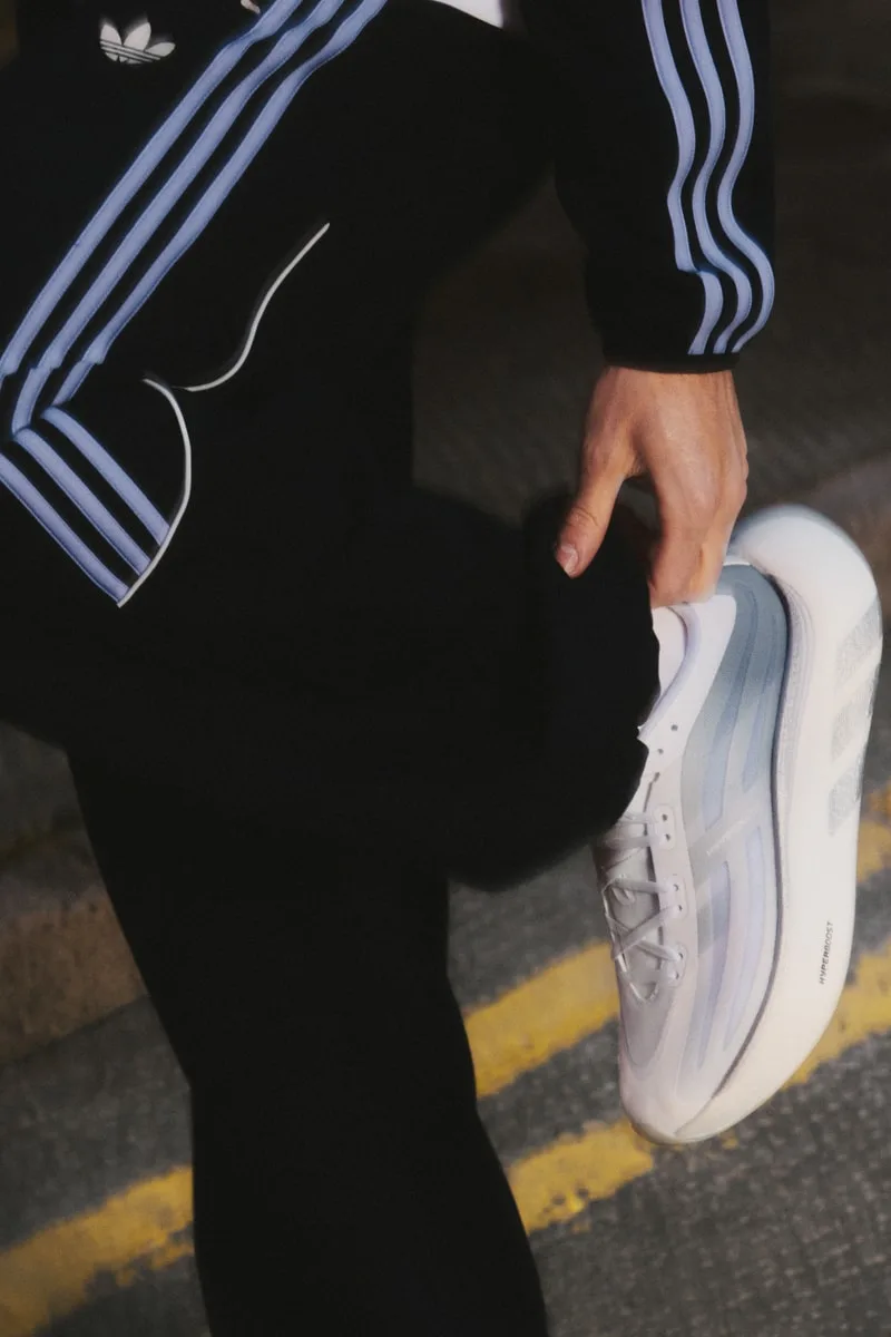 Personne portant un survêtement noir et chaussures blanches tendance.
