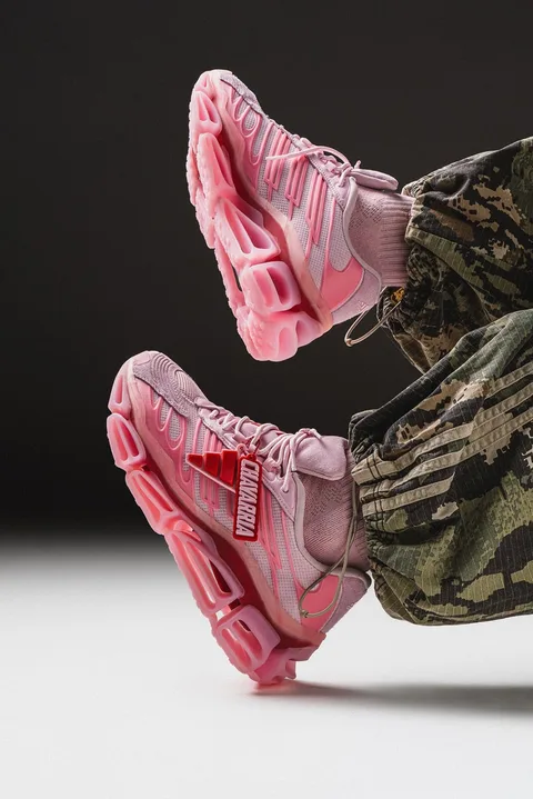Chaussures roses aux semelles épaisses, portées avec pantalon camouflage.