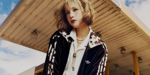 Personne avec une veste Adidas devant une station-service.