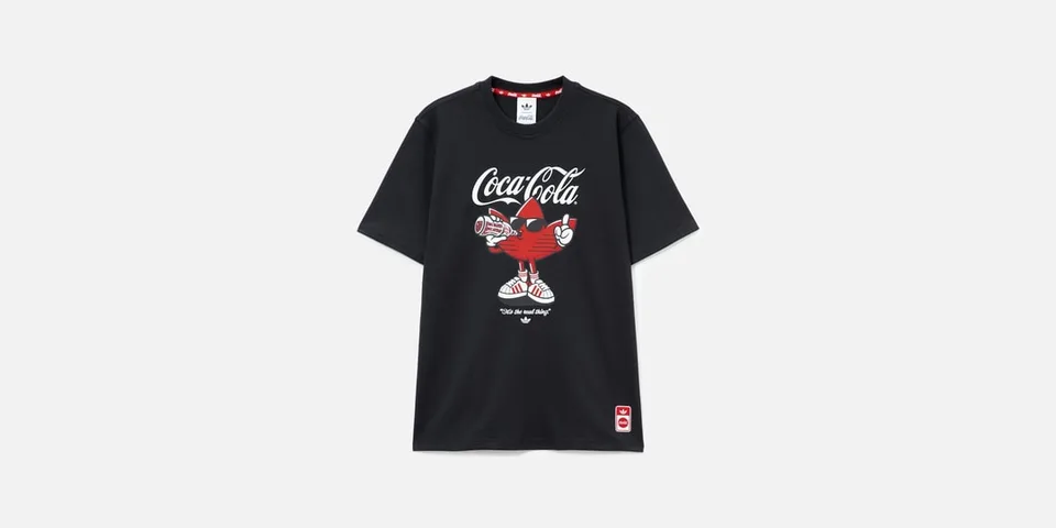 T-shirt noir Coca-Cola avec personnage rouge et bouteille.
