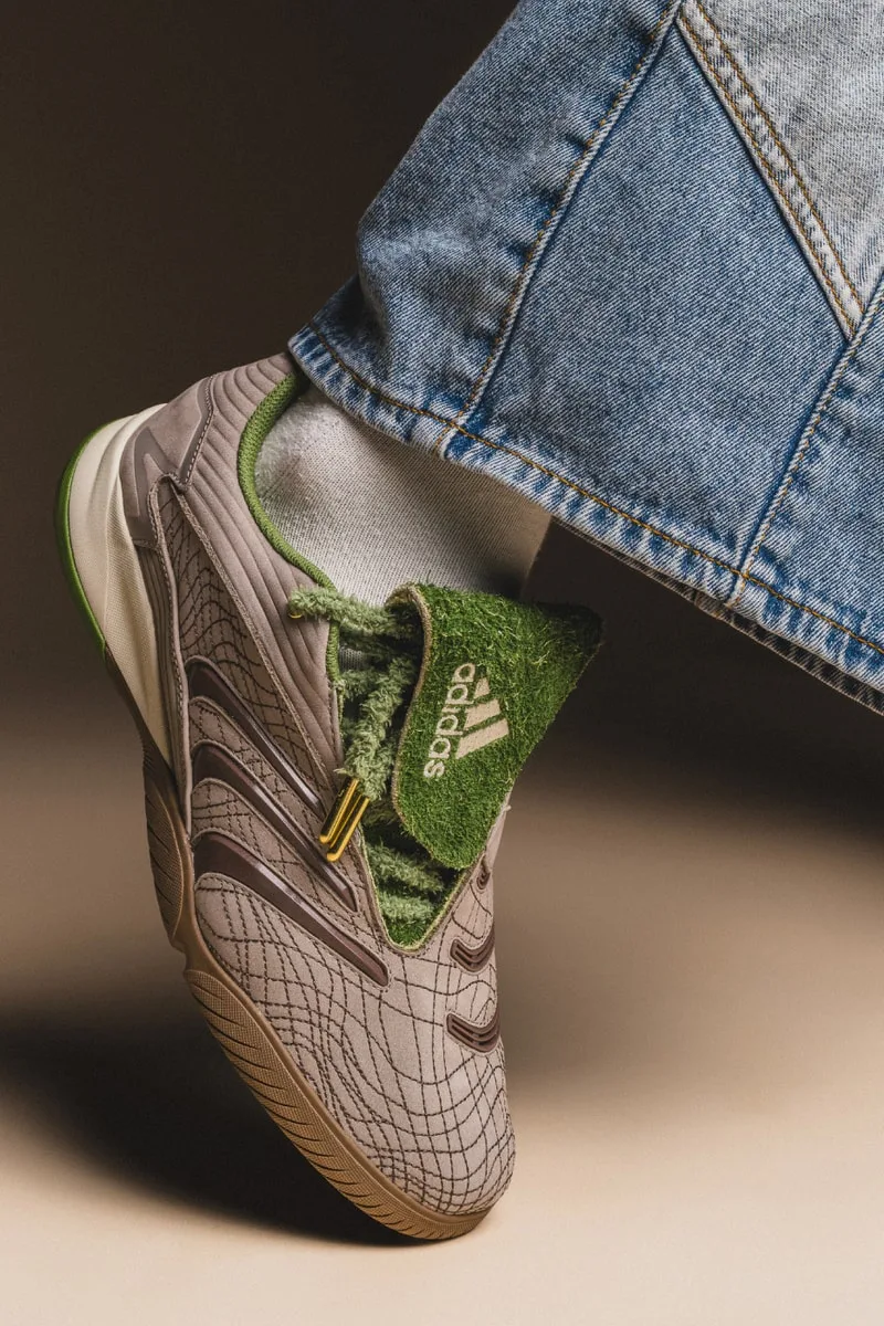Chaussure Adidas grise et verte avec un jean bleu visible.
