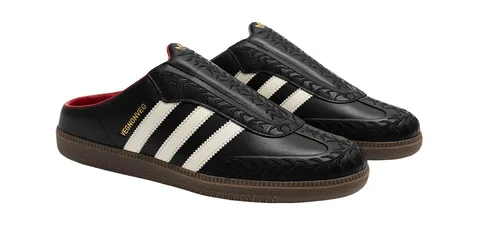 Pantoufles noires avec rayures blanches et semelle marron.