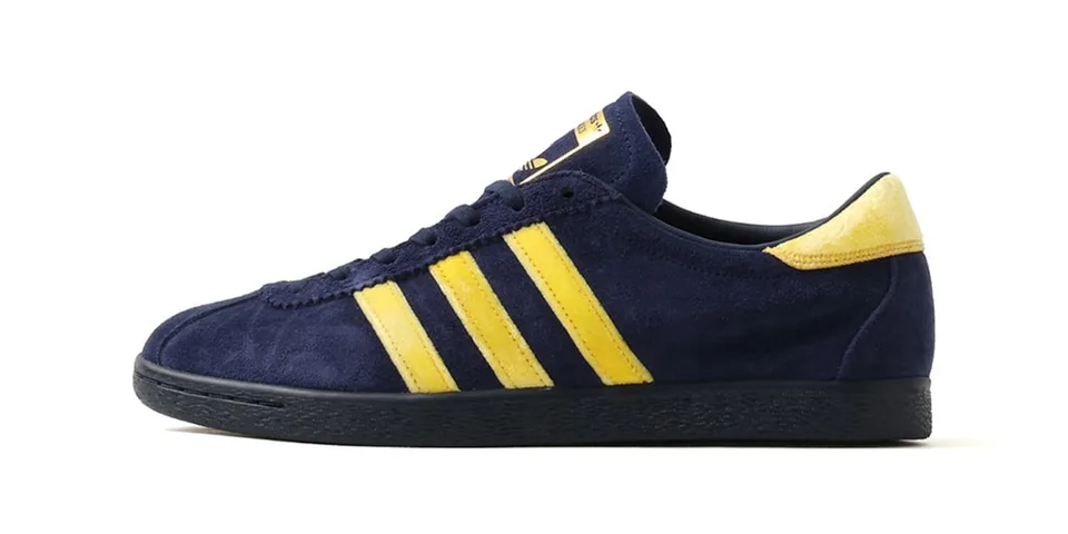 Chaussure bleue avec bandes jaunes, design Adidas classique.