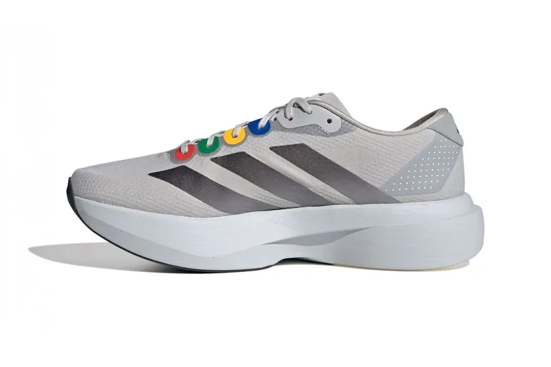 Chaussure de sport grise avec logo coloré et bandes noires.