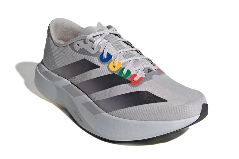Chaussure grise avec rayures noires et œillets colorés.