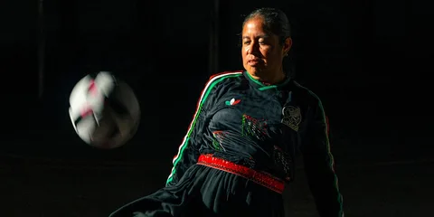 Femme en action avec un ballon de football dans l'obscurité.
