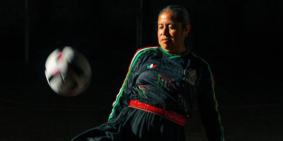 Femme en action avec un ballon de football dans l'obscurité.