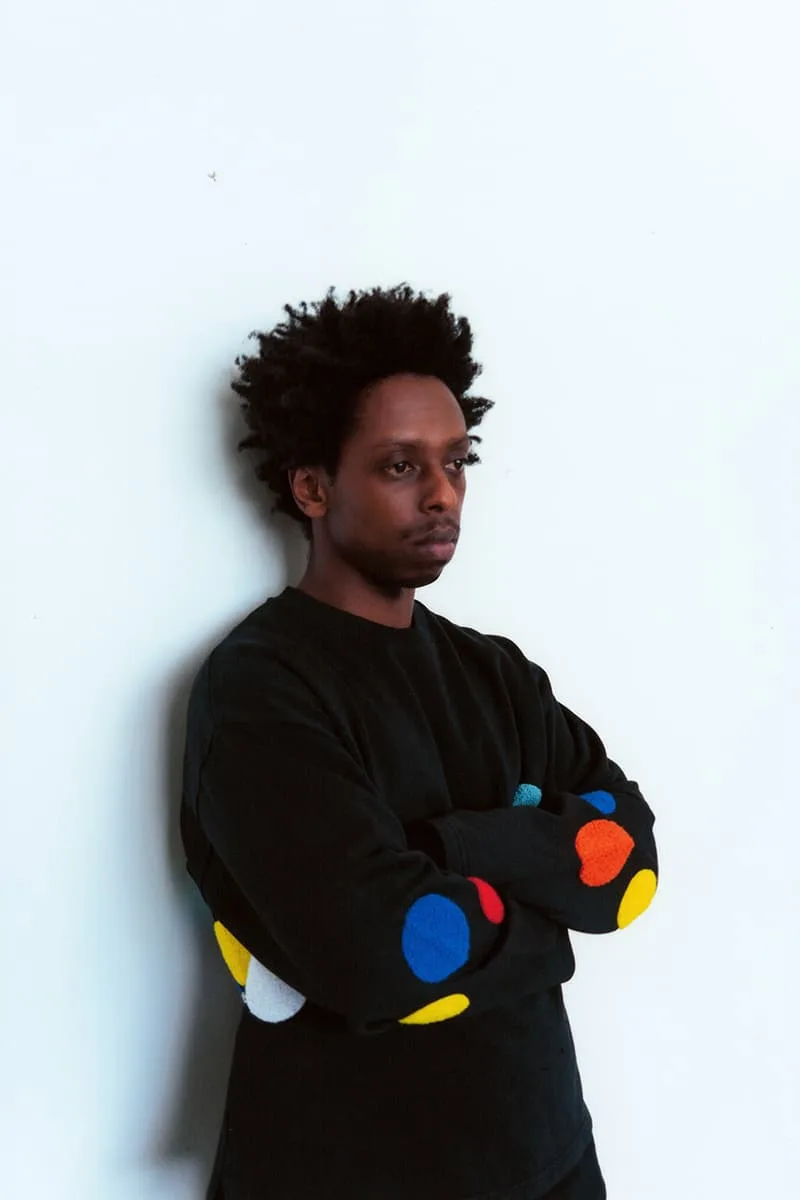 Homme vêtu d'un pull noir avec des motifs colorés.