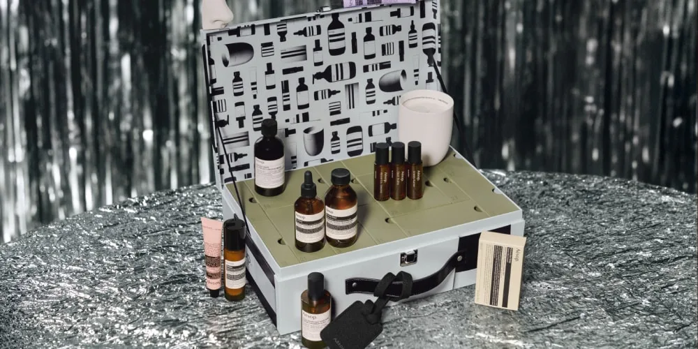 Coffret de cosmétiques avec flacons et pot blanc sur une table argentée.