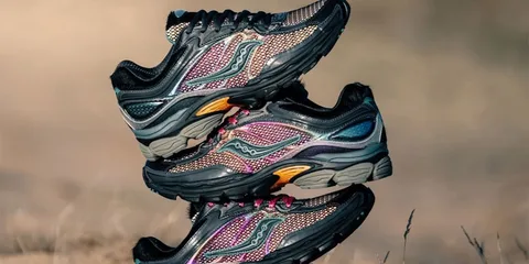Trois baskets de running colorées empilées sur un fond désertique.