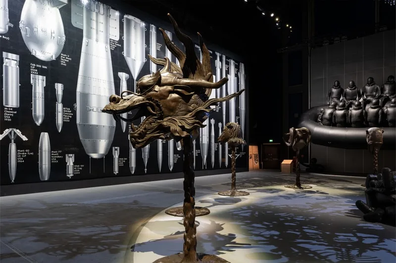 Sculptures de tête de dragon devant un mur avec des schémas d'armes.