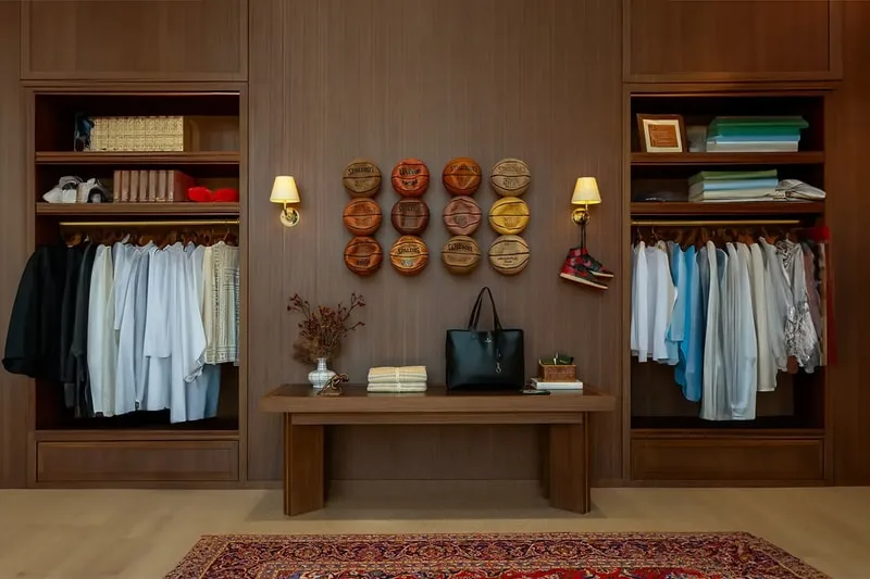 Garde-robe avec vêtements et sacs, mur avec paniers décoratifs.