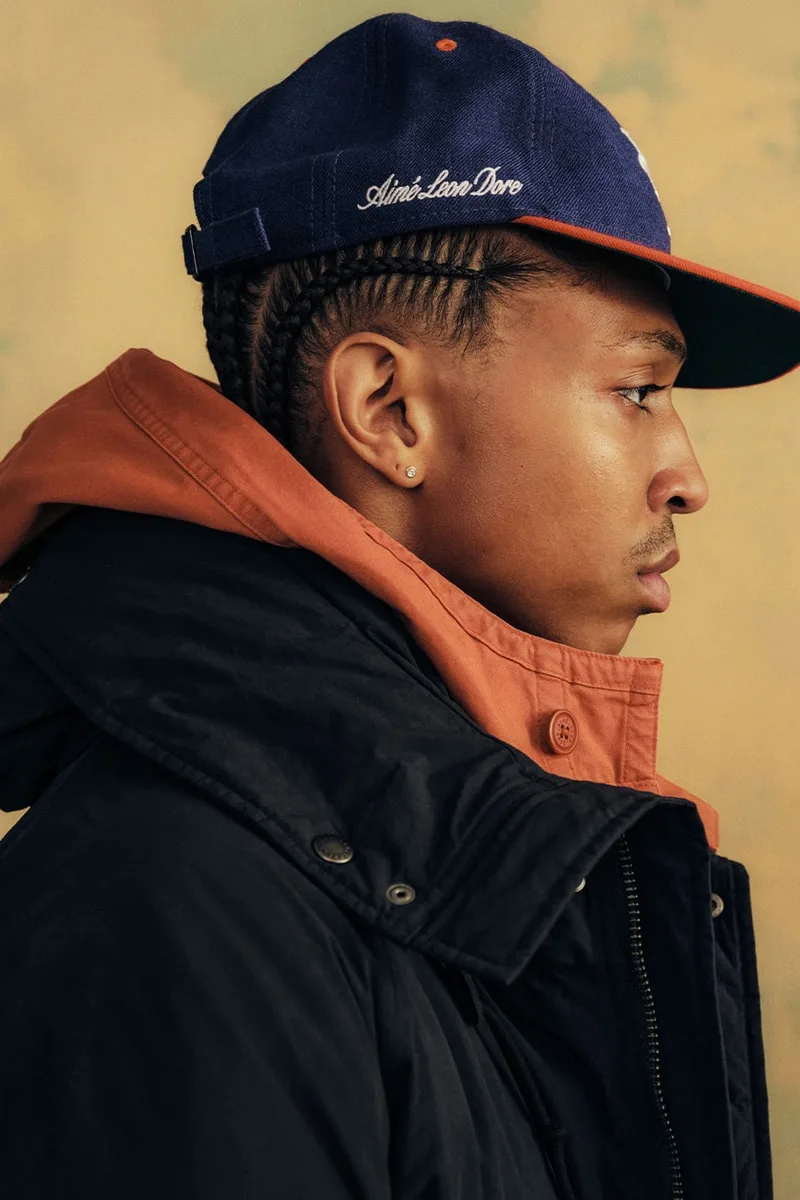 Jeune homme en profil avec casquette et veste, regard pensif.