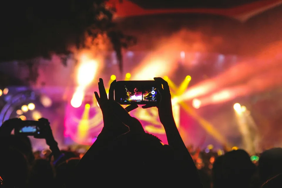 Personne prenant une photo lors d'un concert avec des lumières colorées