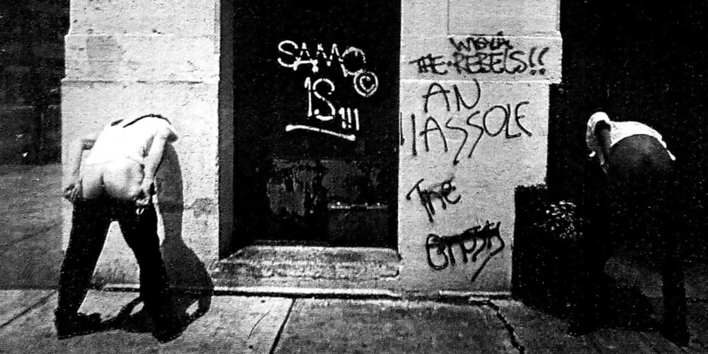 Deux personnes tournant le dos avec des graffitis sur un mur.