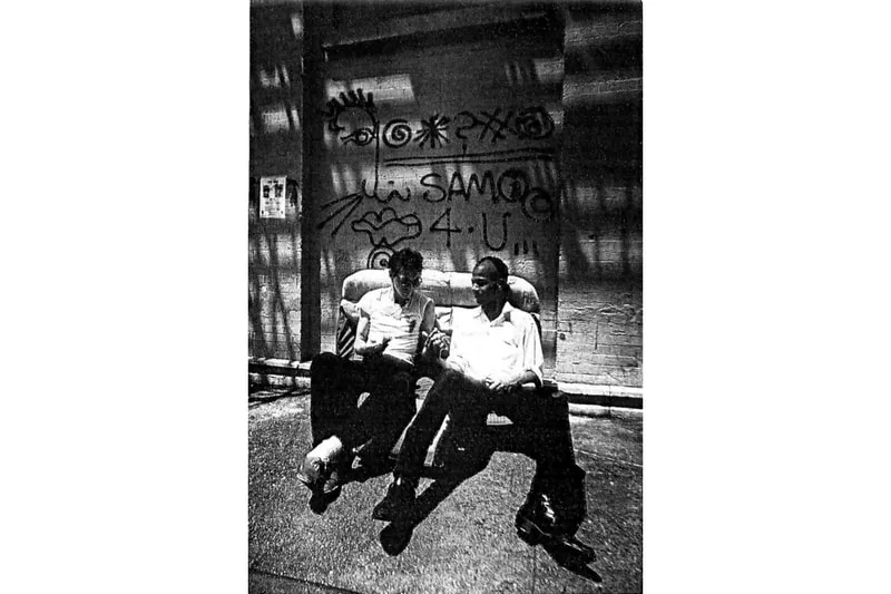 Deux personnes assises sur un canapé devant un graffiti.