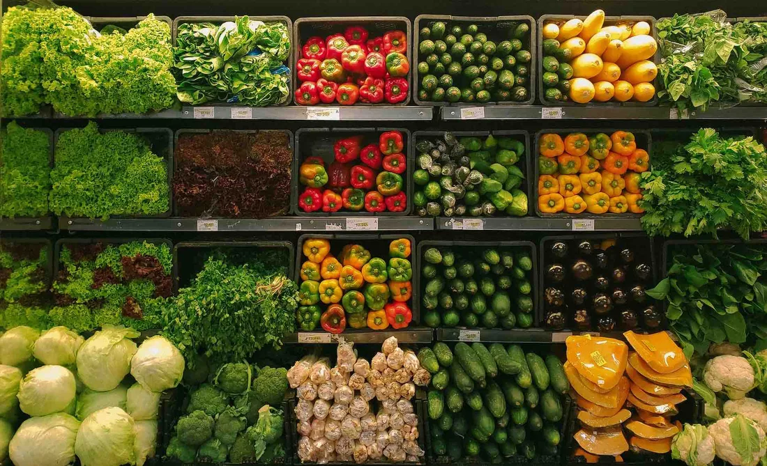 Rayons de supermarché remplis de légumes variés colorés, organisés parfaitement.
