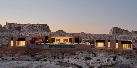 Maison moderne dans un désert avec des collines en arrière-plan.