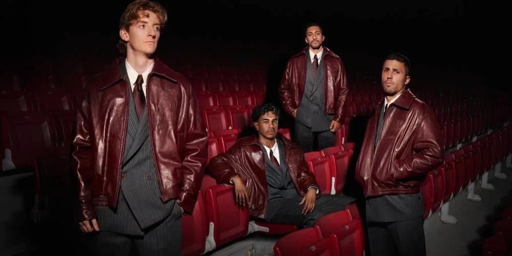 Quatre hommes en vestes de cuir posent dans une salle de cinéma aux sièges rouges.