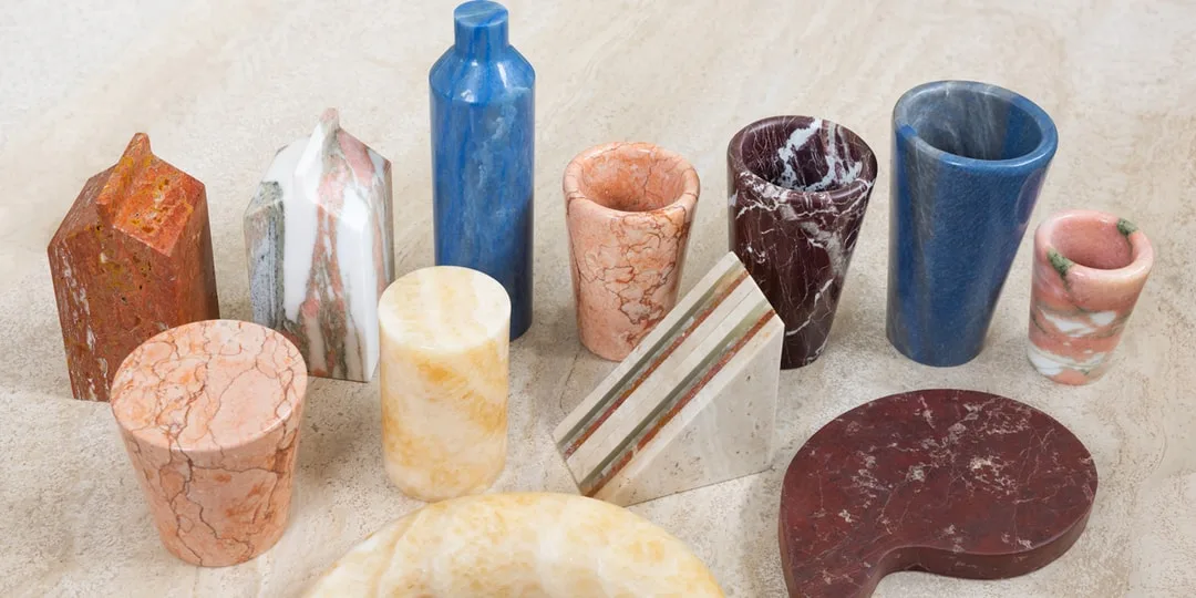 Objets en marbre coloré de formes variées sur une surface en pierre.