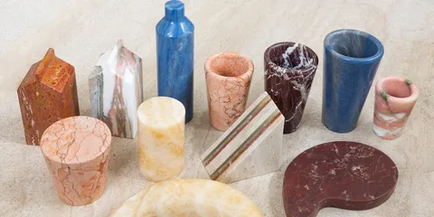 Objets en marbre coloré de formes variées sur une surface en pierre.