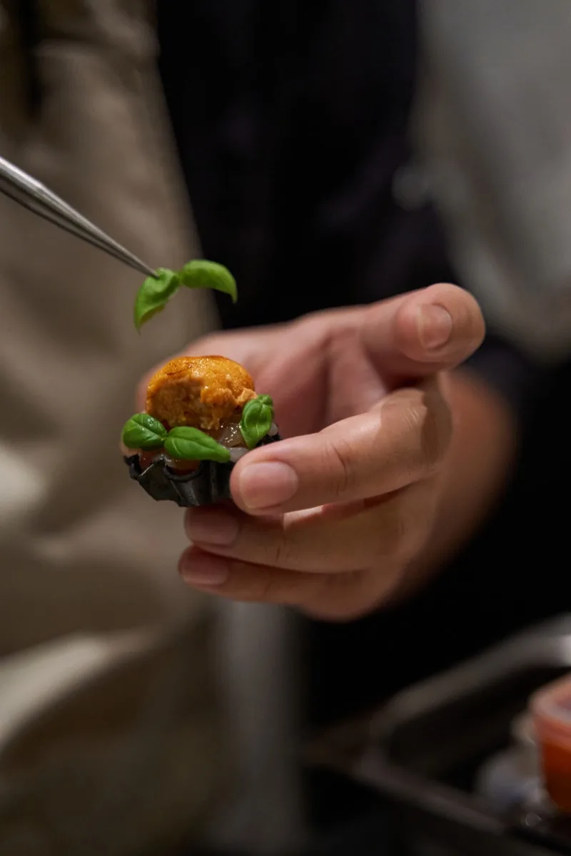 Personne préparant un petit plat raffiné avec basilic.