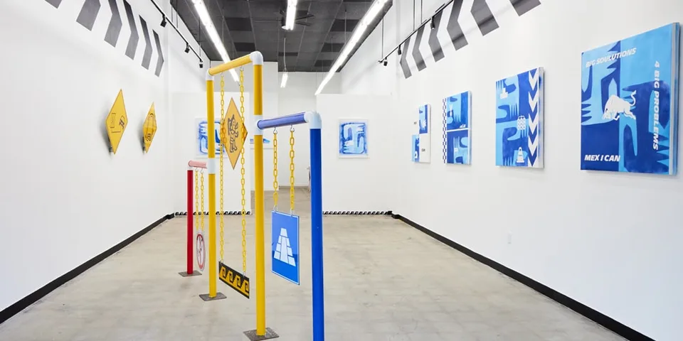 Galerie d'art avec installations et peintures abstraites sur les murs.