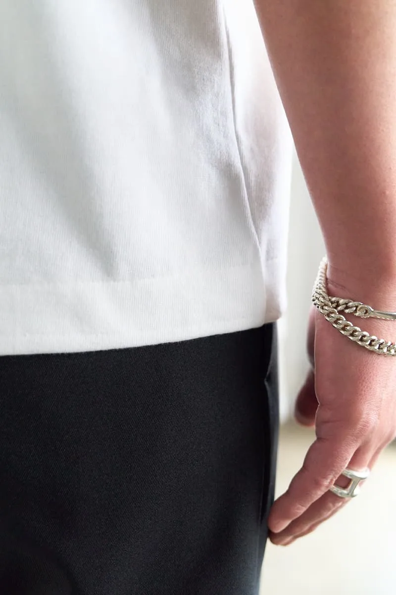 Personne portant un bracelet chaîne et une bague en argent.