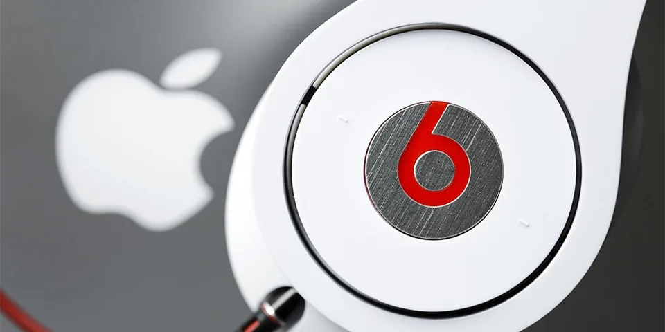 Casque Beats blanc devant un logo Apple argenté