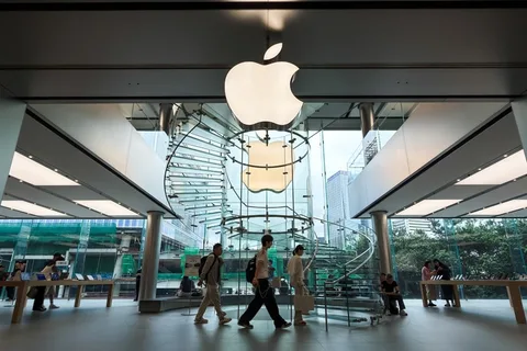 Intérieur du magasin Apple avec logo et escalier en colimaçon, clients entrant.