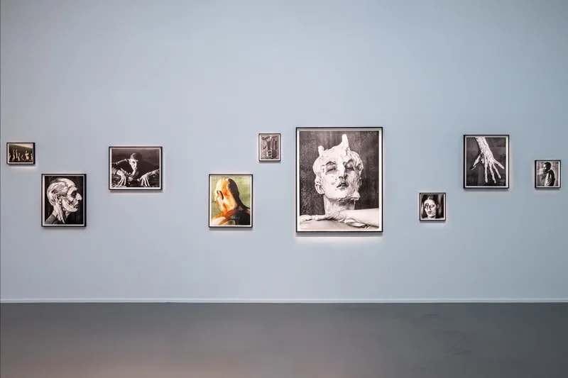 Galerie d'art avec plusieurs photos en noir et blanc sur un mur bleu.