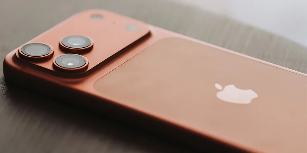 Smartphone rose avec trois caméras et logo d'une pomme sur le dos.