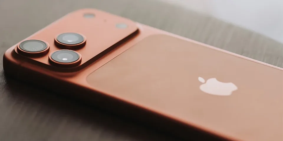 Smartphone rose avec trois caméras et logo d'une pomme sur le dos.