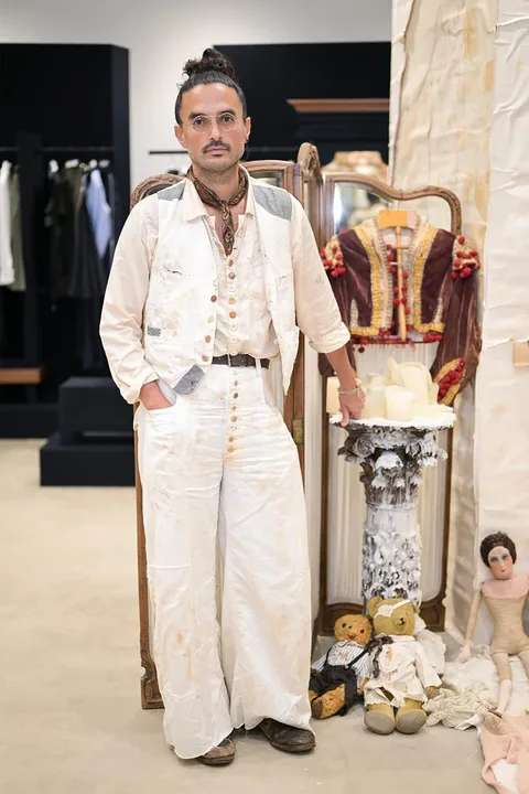 Homme en tenue vintage blanche avec accessoires, devant un miroir.