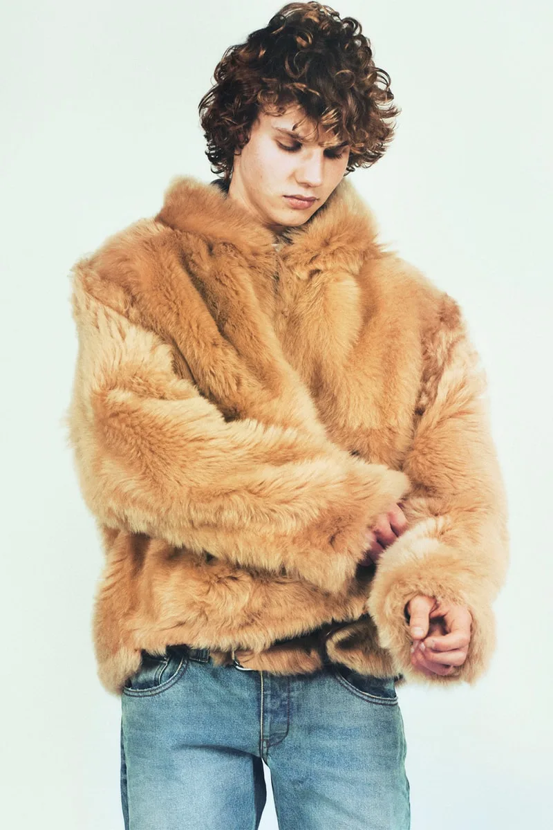 Jeune homme avec un manteau en fausse fourrure et jean.